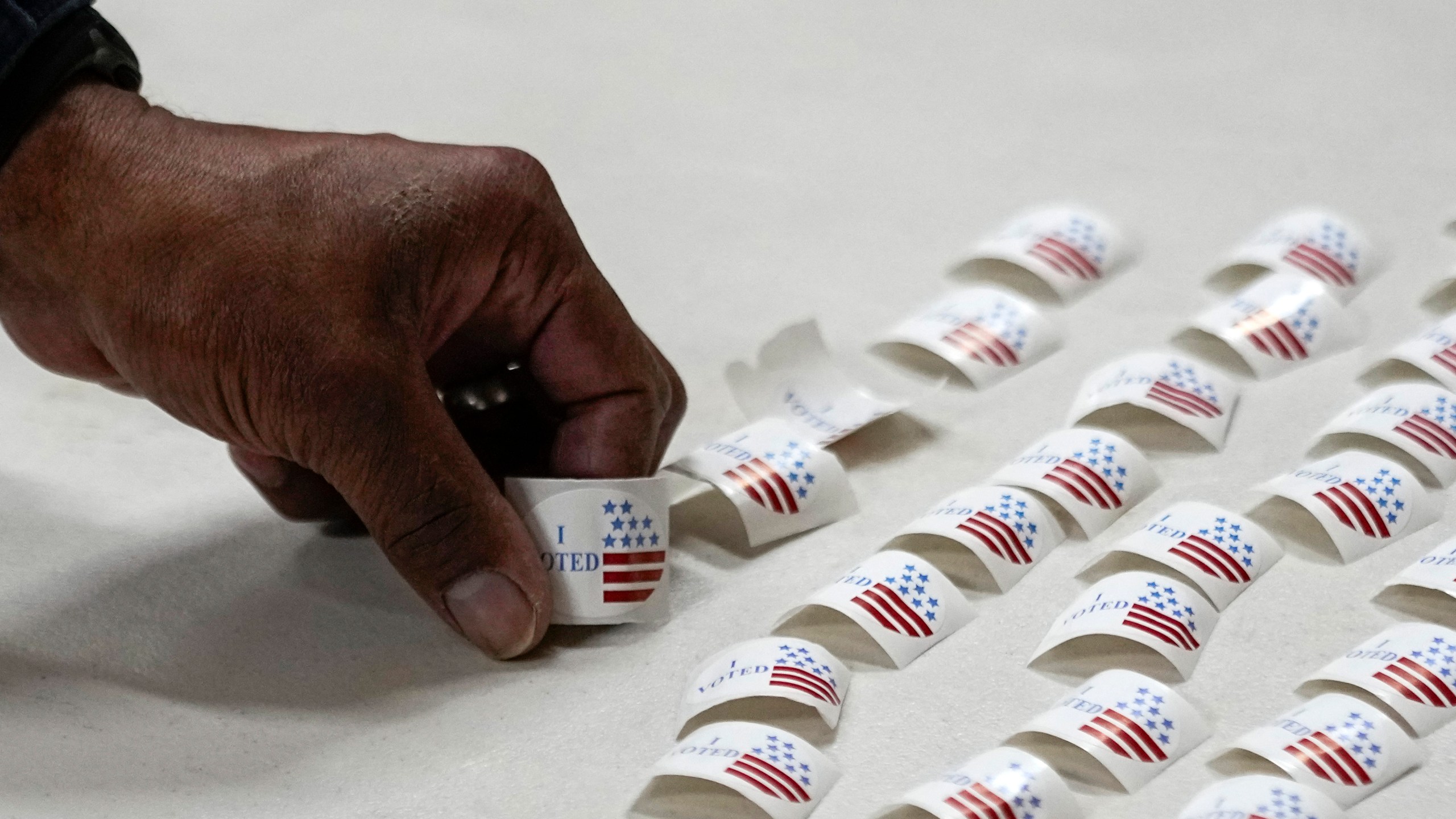 A voter picks up a sticker after voting at a polling place.