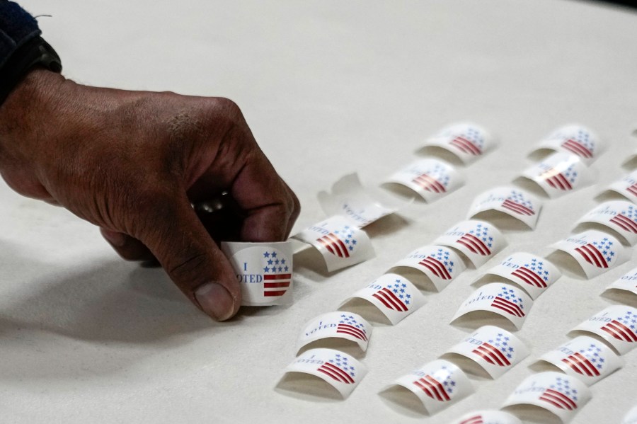 A voter picks up a sticker after voting at a polling place.