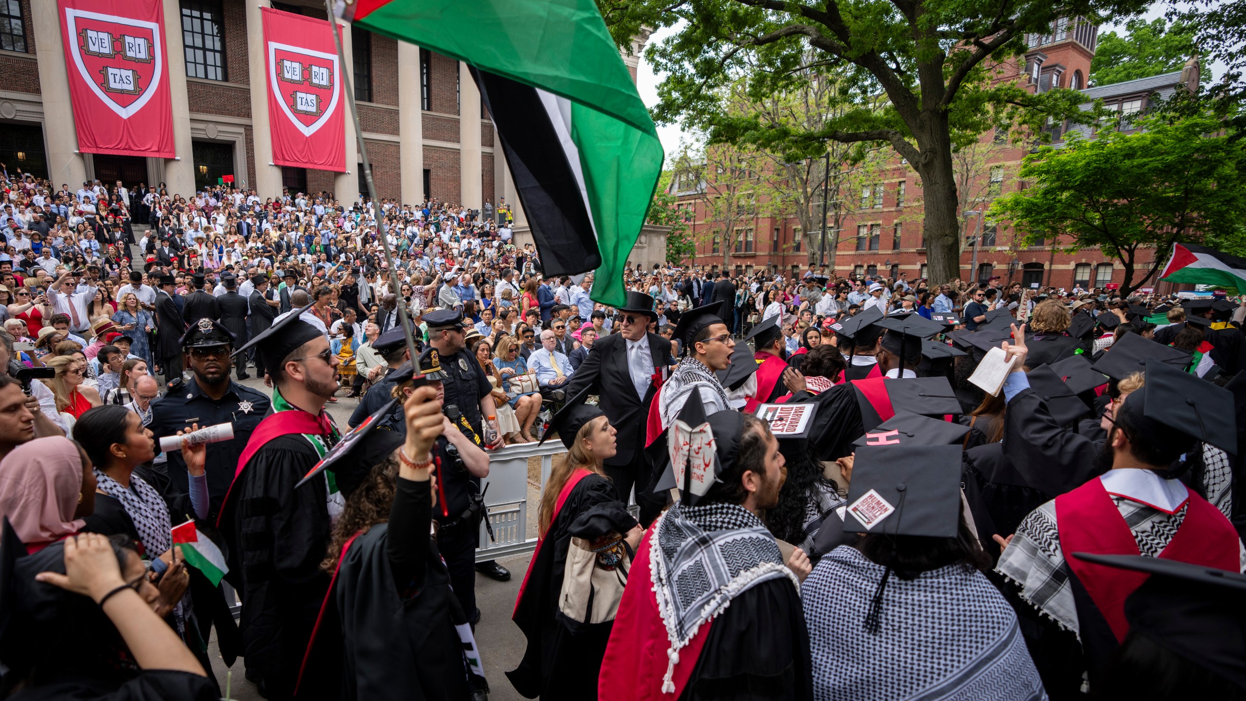 FILE - Graduating students hold Palestinian flags and chant as they walk out in protest over the 13 students who have been barred from graduating due to protest activities, during commencement in Harvard Yard, at Harvard University, in Cambridge, Mass., Thursday, May 23, 2024. (AP Photo/Ben Curtis, File)