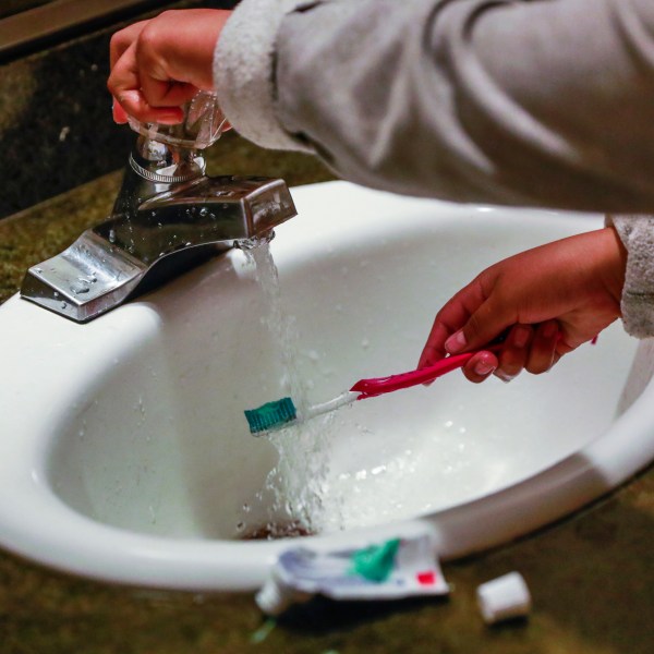 A child rinses a toothbrush in San Francisco on June 18, 2019.