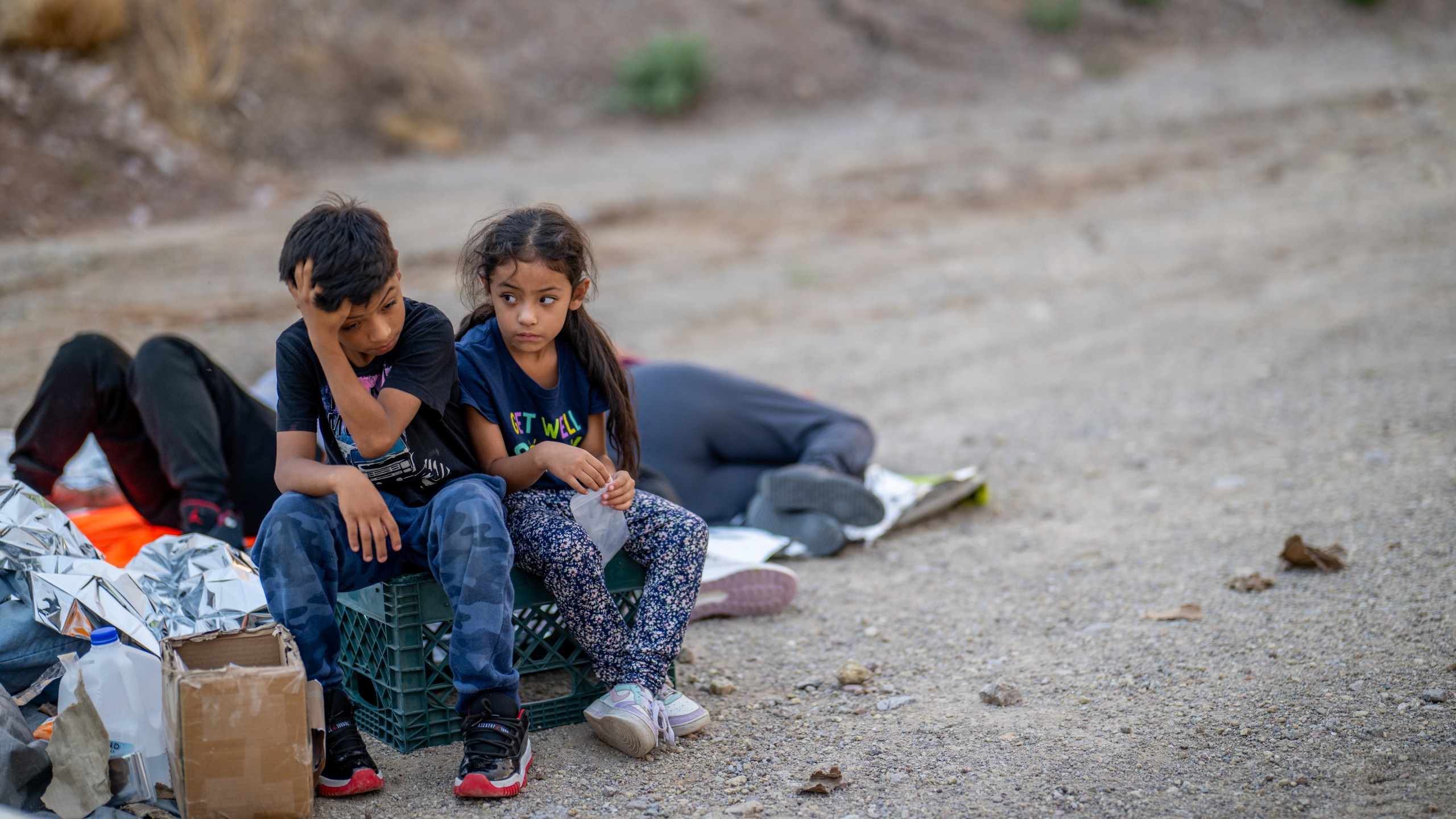 Children look towards the sky while waiting to be apprehended.