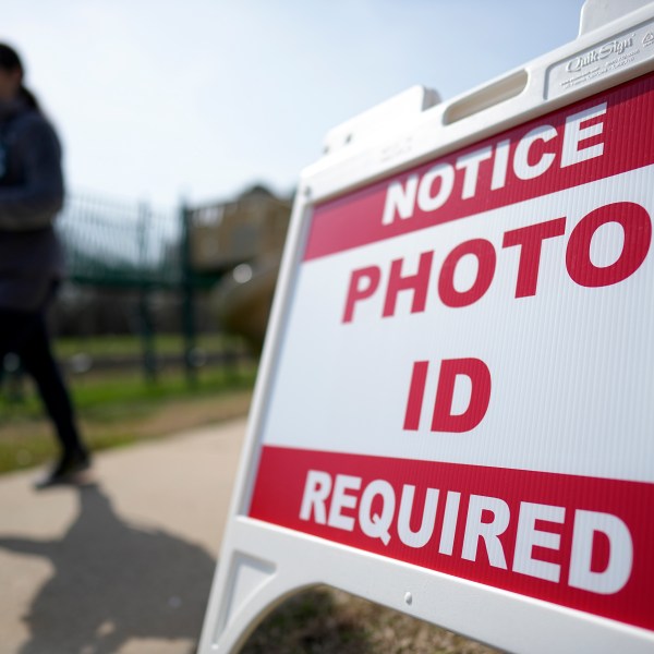 FILE - A Super Tuesday voter walks past a sign requiring a photo ID at a polling location, March 5, 2024, in Mount Holly, N.C. (AP Photo/Chris Carlson, File)