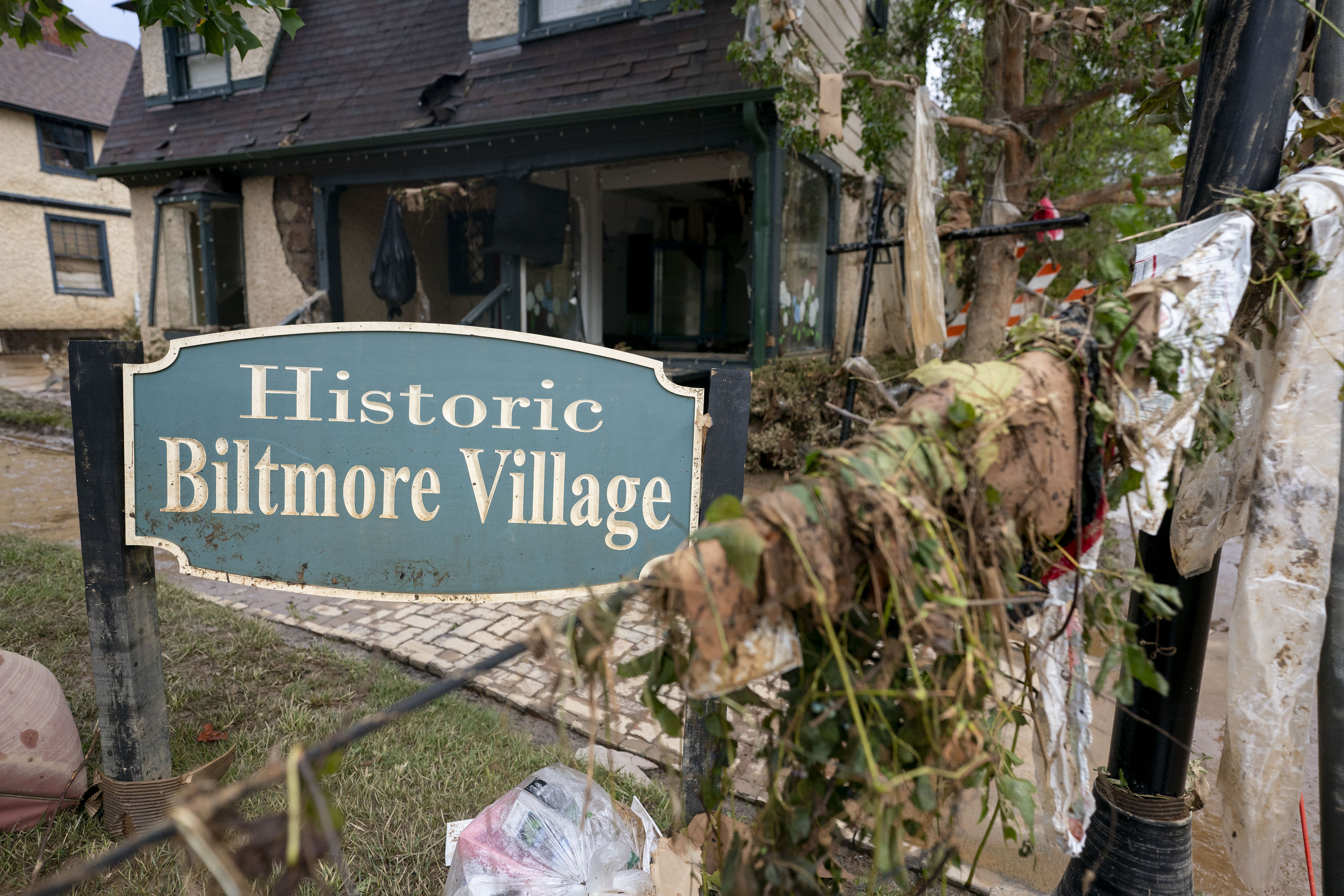 A sign for Biltmore village surrounded by debris