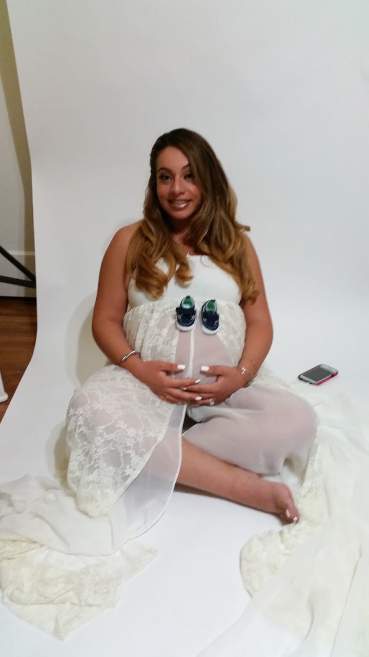 A dark-haired woman in a white sheet doing a maternity photo shoot.