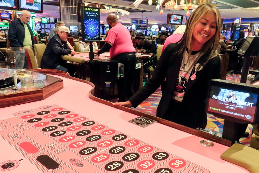 Lee Johnson, a games manager at the Hard Rock casino, checks a roulette table covered in pink felt for breast cancer awareness month before it opens for use in Atlantic City, N.J., Thursday, Oct. 3, 2024. (AP Photo/Wayne Parry)