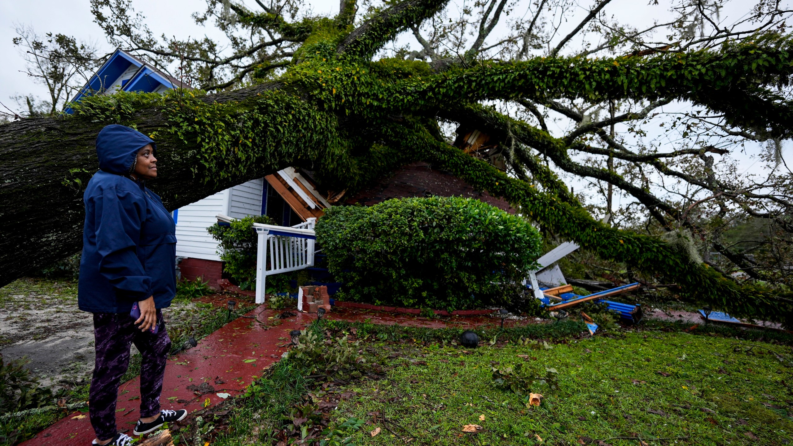 FILE - Rhonda Bell looks on after an Oak tree landed on her 100-year-old home after Hurricane Helene moved through, Friday, Sept. 27, 2024, in Valdosta, Ga. (AP Photo/Mike Stewart, File)