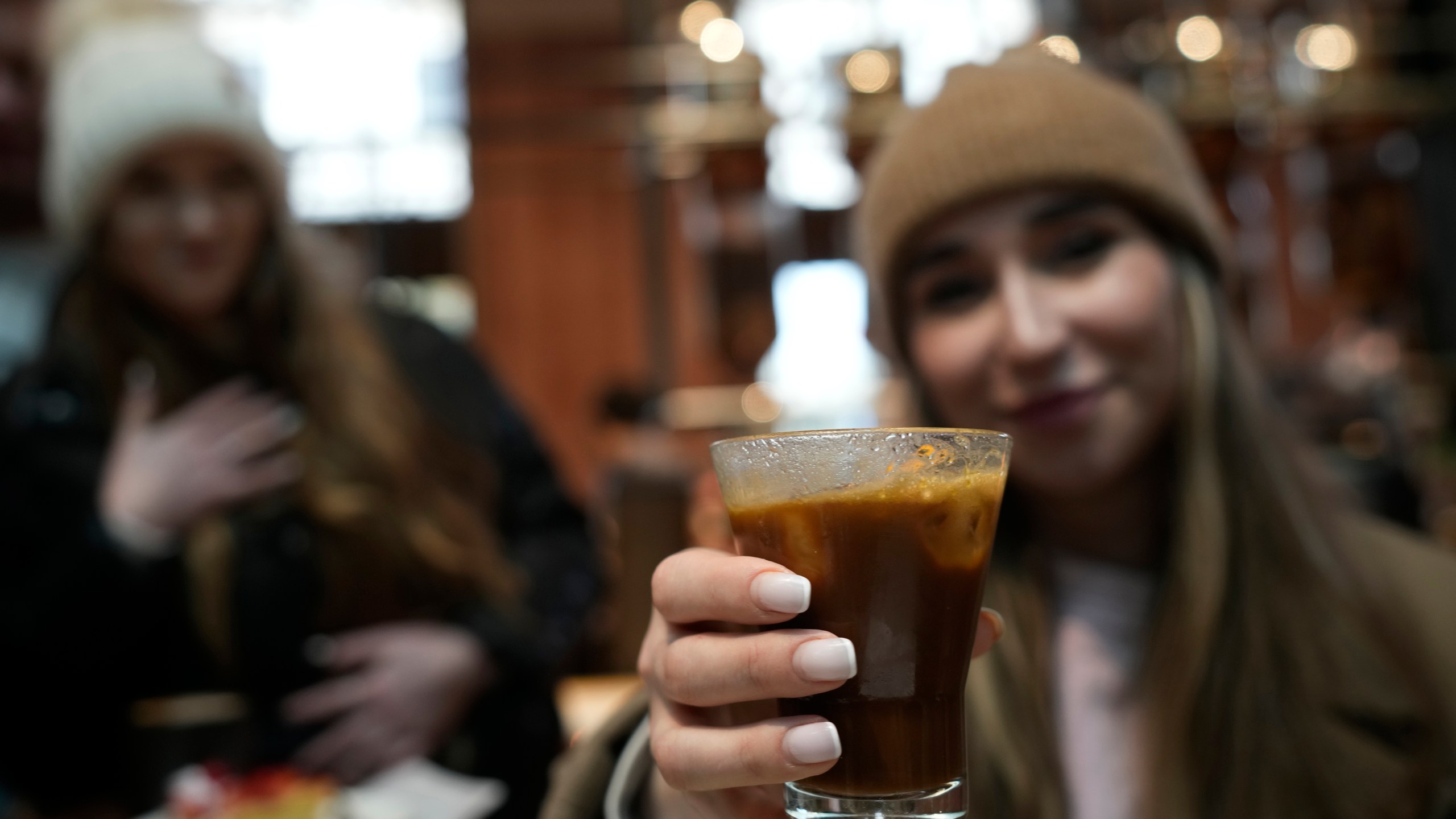 FILE - Kaya Cupial, right, shows her Oleato Iced Cortado coffee at the Starbucks coffee shop in Milan, Italy, Feb. 27, 2023. (AP Photo/Antonio Calanni, File)