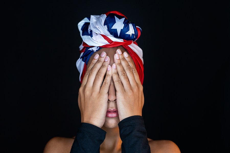 Horizontal close up view of mixed race woman isolated on black background wearing an American Flag. protests concept.