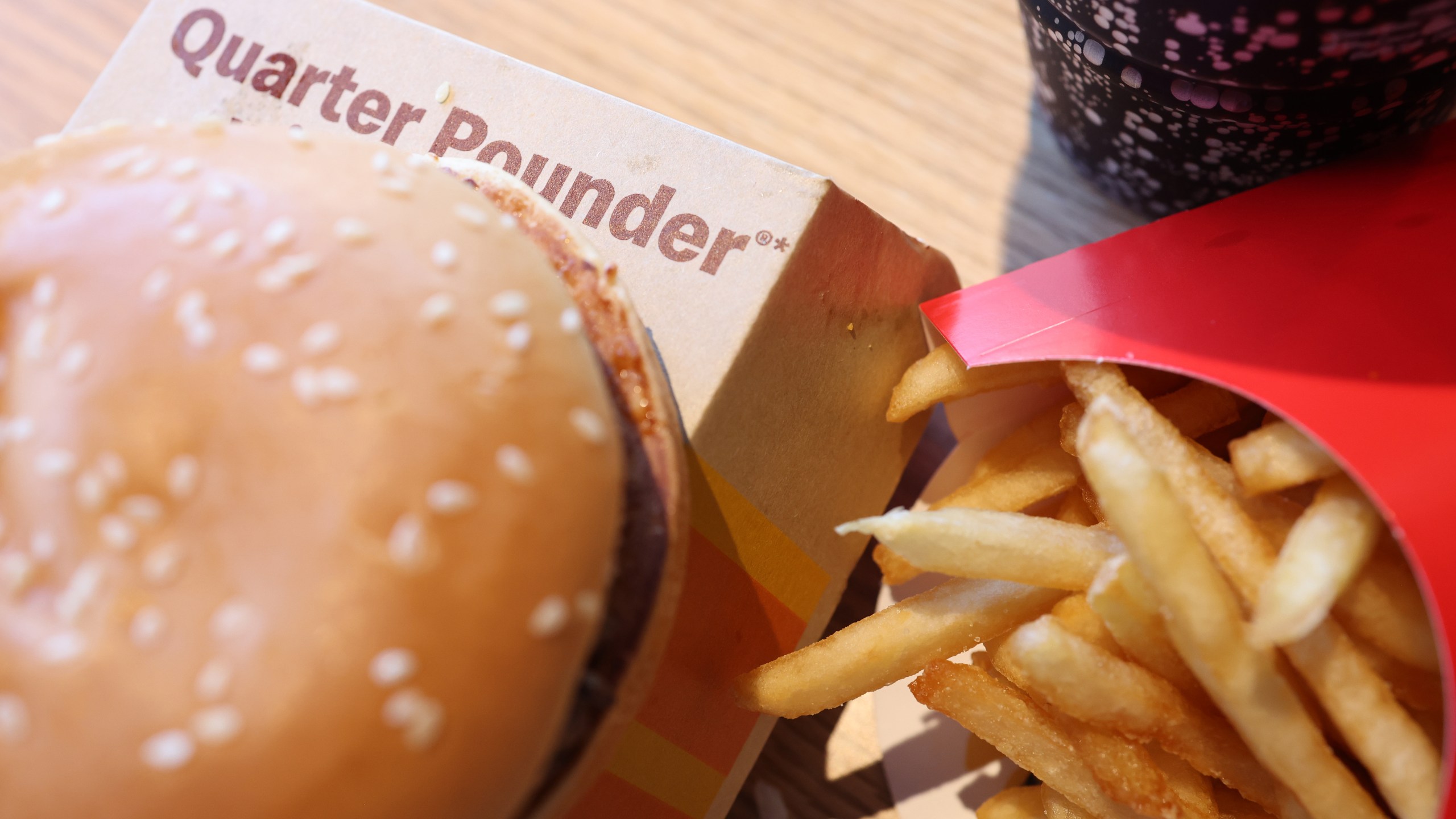 A burger sits on top of a box labeled "Quarter Pounder" next to an order of McDonald's fries.