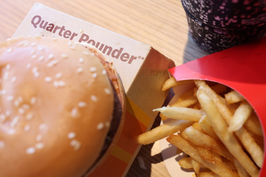A burger sits on top of a box labeled "Quarter Pounder" next to an order of McDonald's fries.