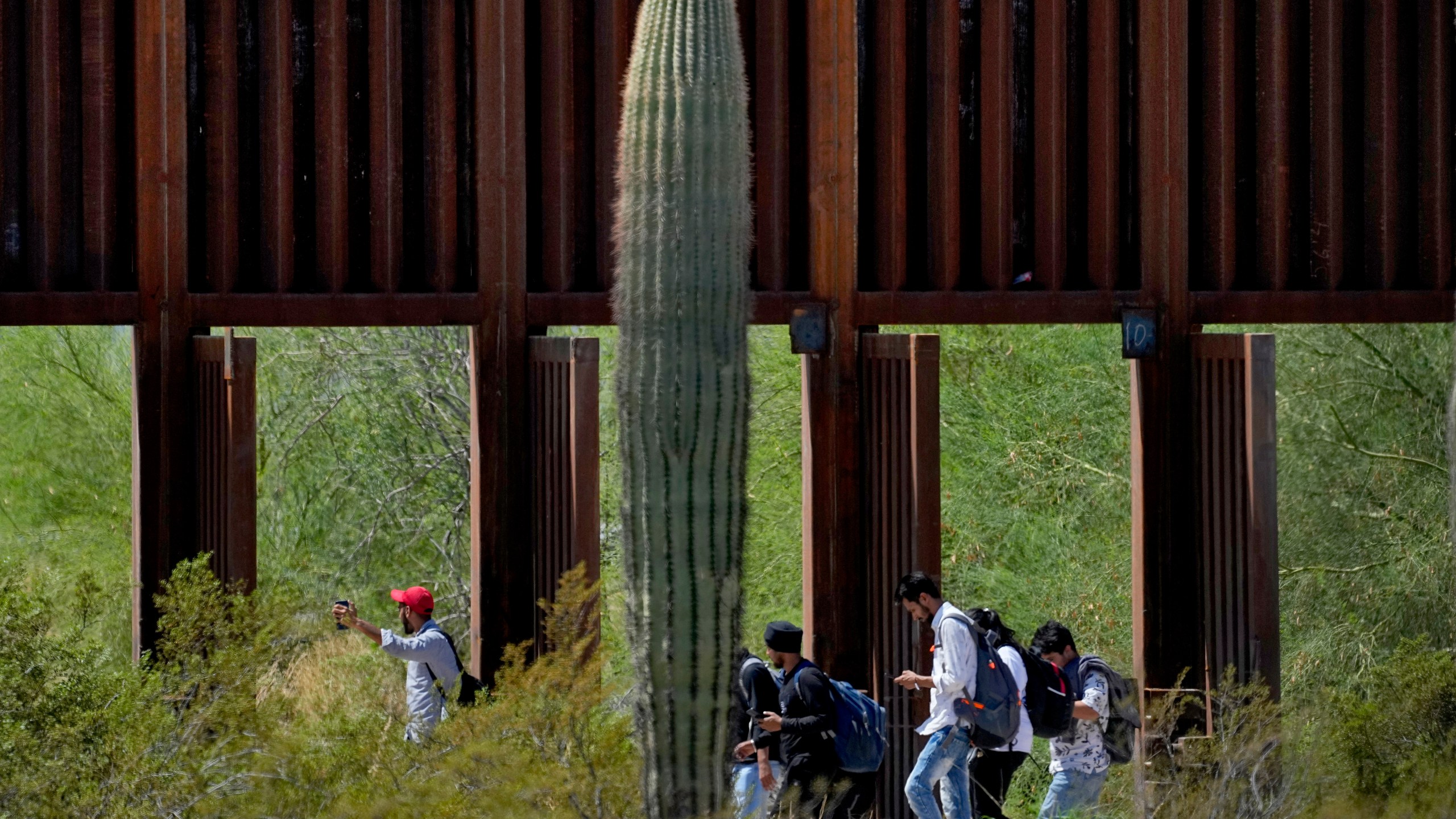 FILE - A group claiming to be from India walk past open border wall storm gates after crossing through the border fence in the Tucson Sector of the U.S.-Mexico border, Aug. 29, 2023, in Organ Pipe Cactus National Monument near Lukeville, Ariz. (AP Photo/Matt York, File)