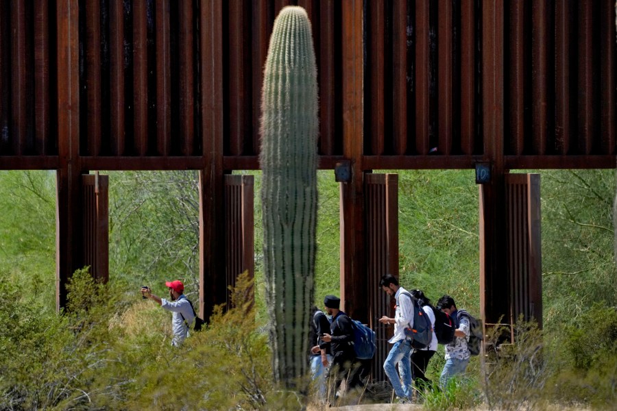 FILE - A group claiming to be from India walk past open border wall storm gates after crossing through the border fence in the Tucson Sector of the U.S.-Mexico border, Aug. 29, 2023, in Organ Pipe Cactus National Monument near Lukeville, Ariz. (AP Photo/Matt York, File)