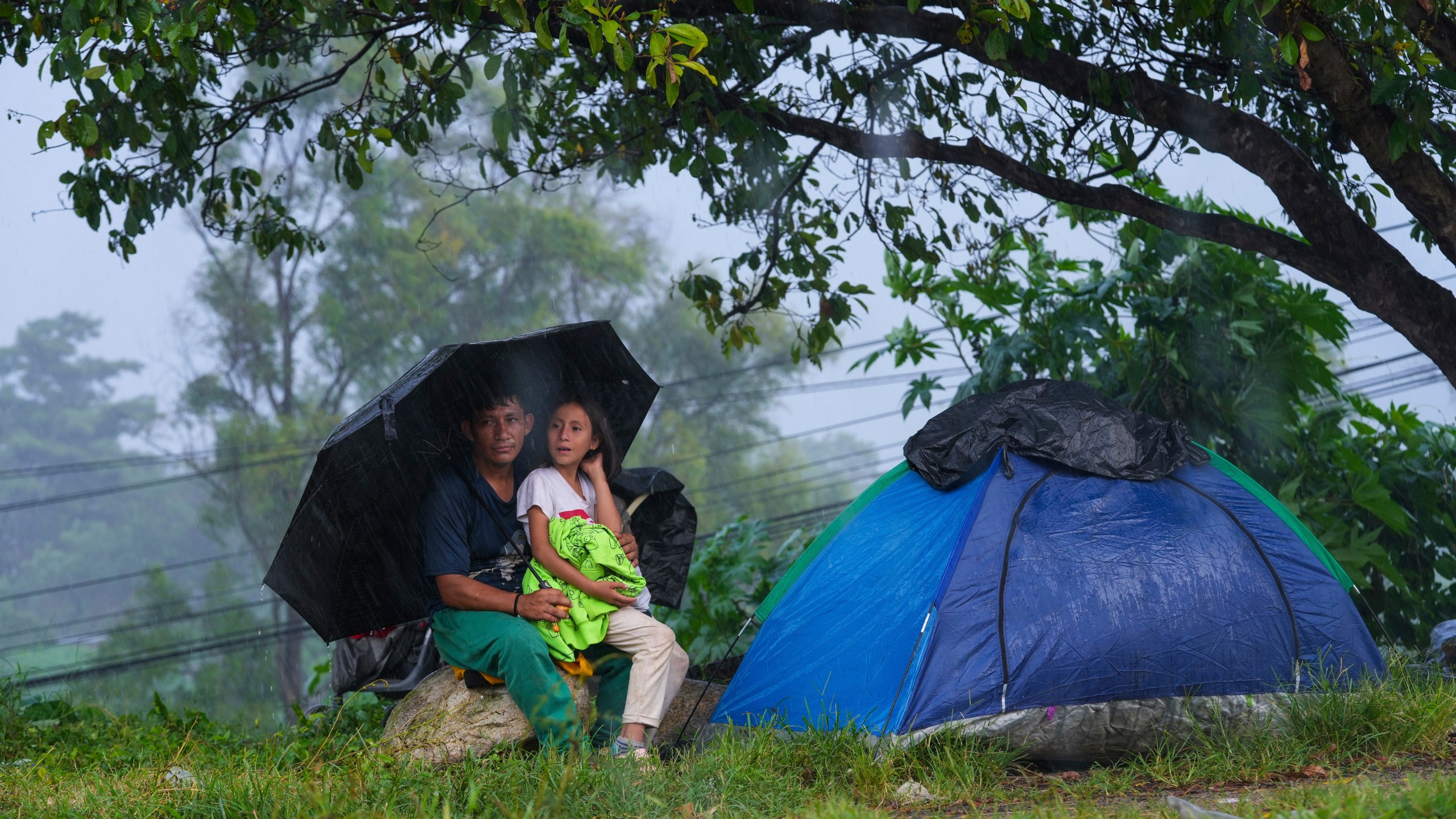 Migrants take cover from the rain after arriving at a makeshift shelter in Huixtla, Chiapas state, Mexico, Wednesday, Nov. 6, 2024, hoping to reach the country's northern border and ultimately the United States. (AP Photo/Moises Castillo)