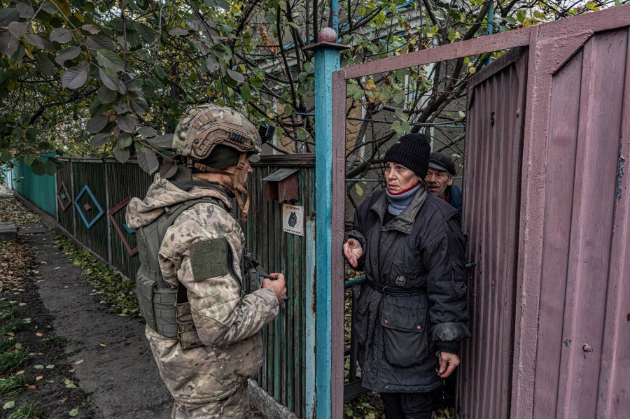 Pipa Vasyl, a policeman of the "White Angels", tries to convince a local woman to evacuate from Kurakhove, Donetsk region, Ukraine, on Nov. 7, 2024. (AP Photo/Anton Shtuka)