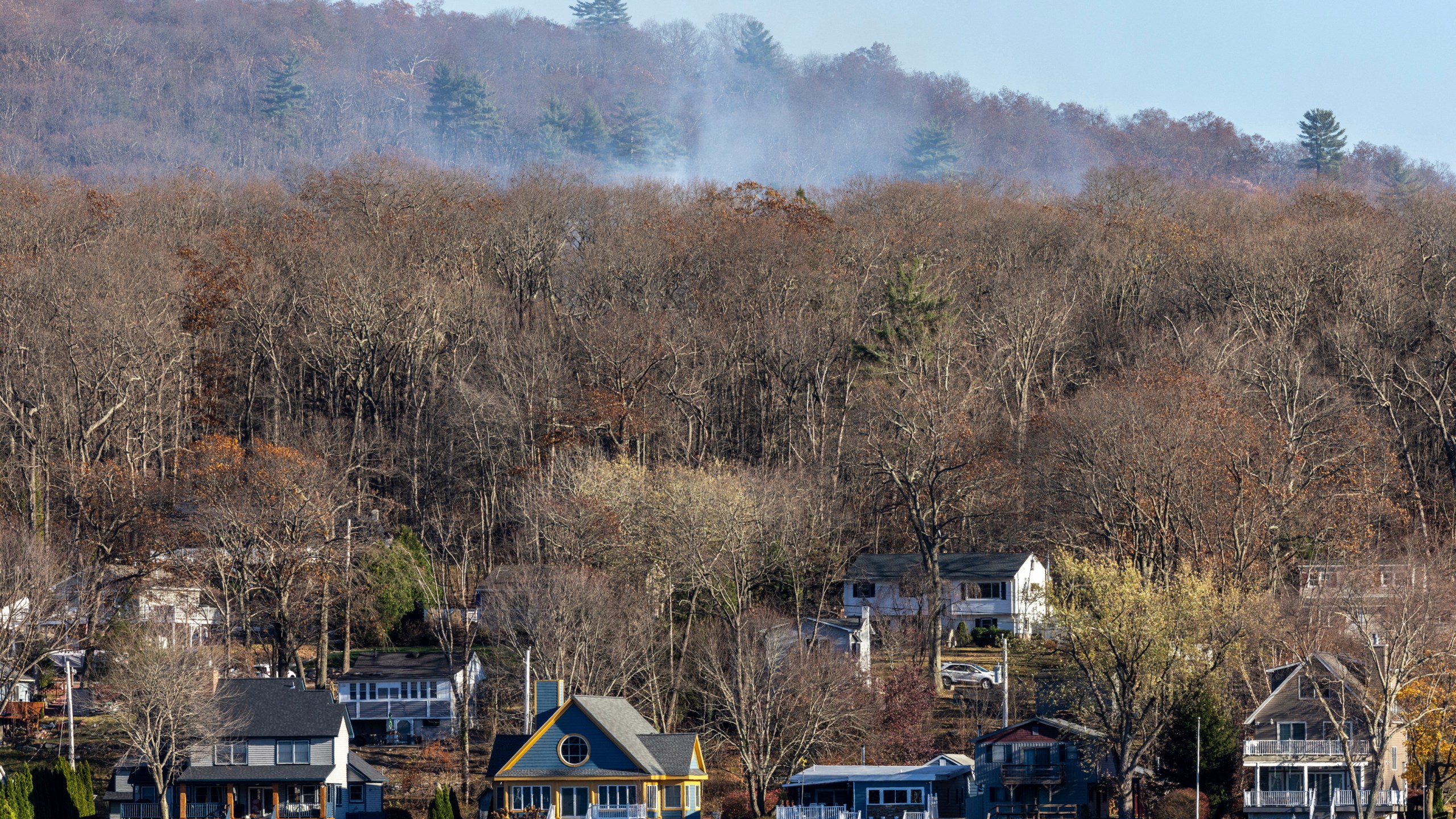 Smoke rises from a wildfire behind a row of lakefront properties in the town of Awosting, as seen from across Greenwood Lake, Lakeside, N.J., Monday, Nov. 11, 2024. (AP Photo/Stefan Jeremiah)