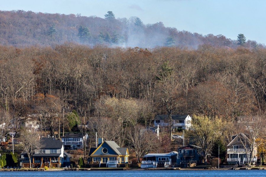 Smoke rises from a wildfire behind a row of lakefront properties in the town of Awosting, as seen from across Greenwood Lake, Lakeside, N.J., Monday, Nov. 11, 2024. (AP Photo/Stefan Jeremiah)