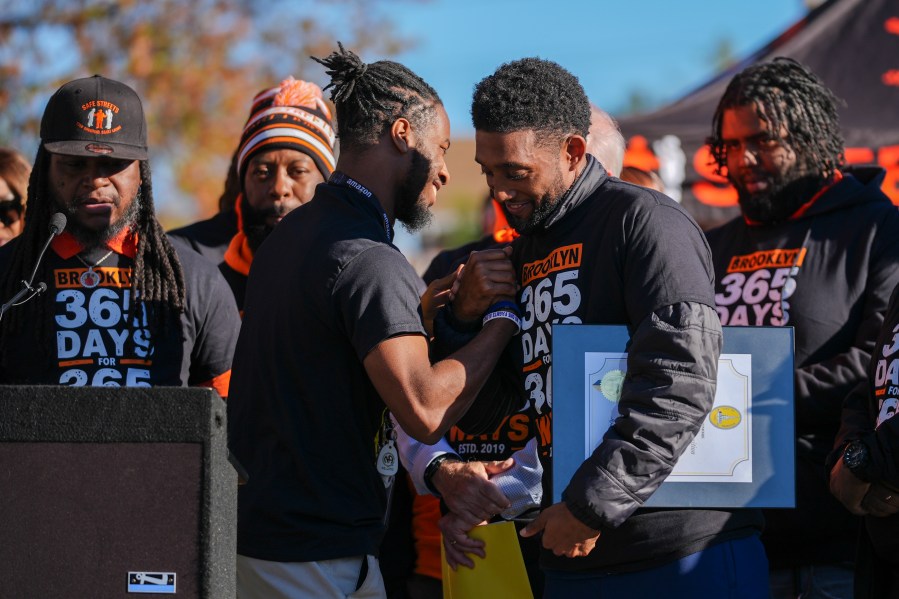 Baltimore Mayor Brandon Scott, right, embraces Adanus Sprillium during a press conference to celebrate achieving over 365 days without a homicide within the Brooklyn neighborhood Safe Streets catchment zone, Tuesday, Nov. 12, 2024, in Baltimore. (AP Photo/Stephanie Scarbrough)