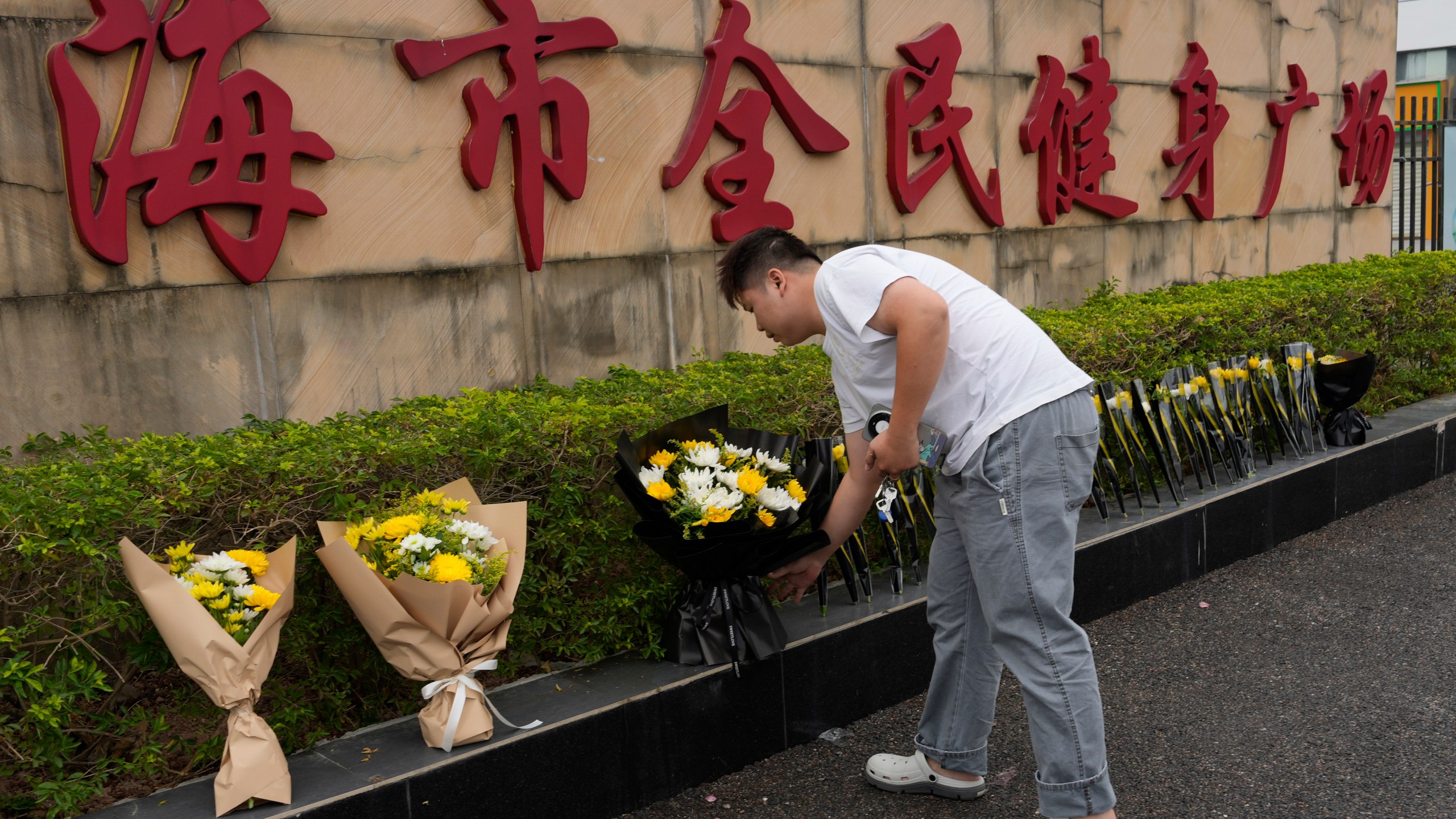 A man lays flowers outside the "Zhuhai People's Fitness Plaza" where a man rammed his car into people exercising at the sports center, in Zhuhai in southern China's Guangdong province on Wednesday, Nov. 13, 2024. (AP Photo/Ng Han Guan)