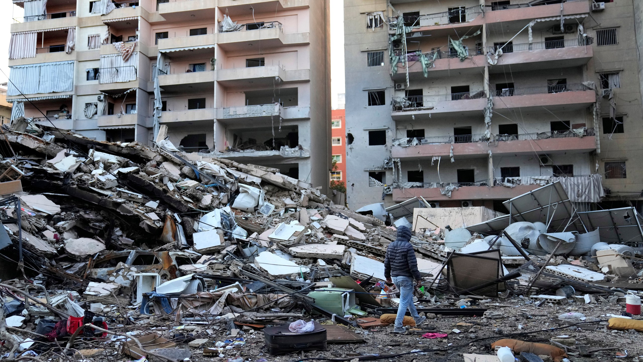 A man passes in front of destroyed buildings that were hit in an Israeli airstrike in Dahiyeh, in the southern suburb of Beirut, Lebanon, Thursday, Nov. 14, 2024. (AP Photo/Hussein Malla)