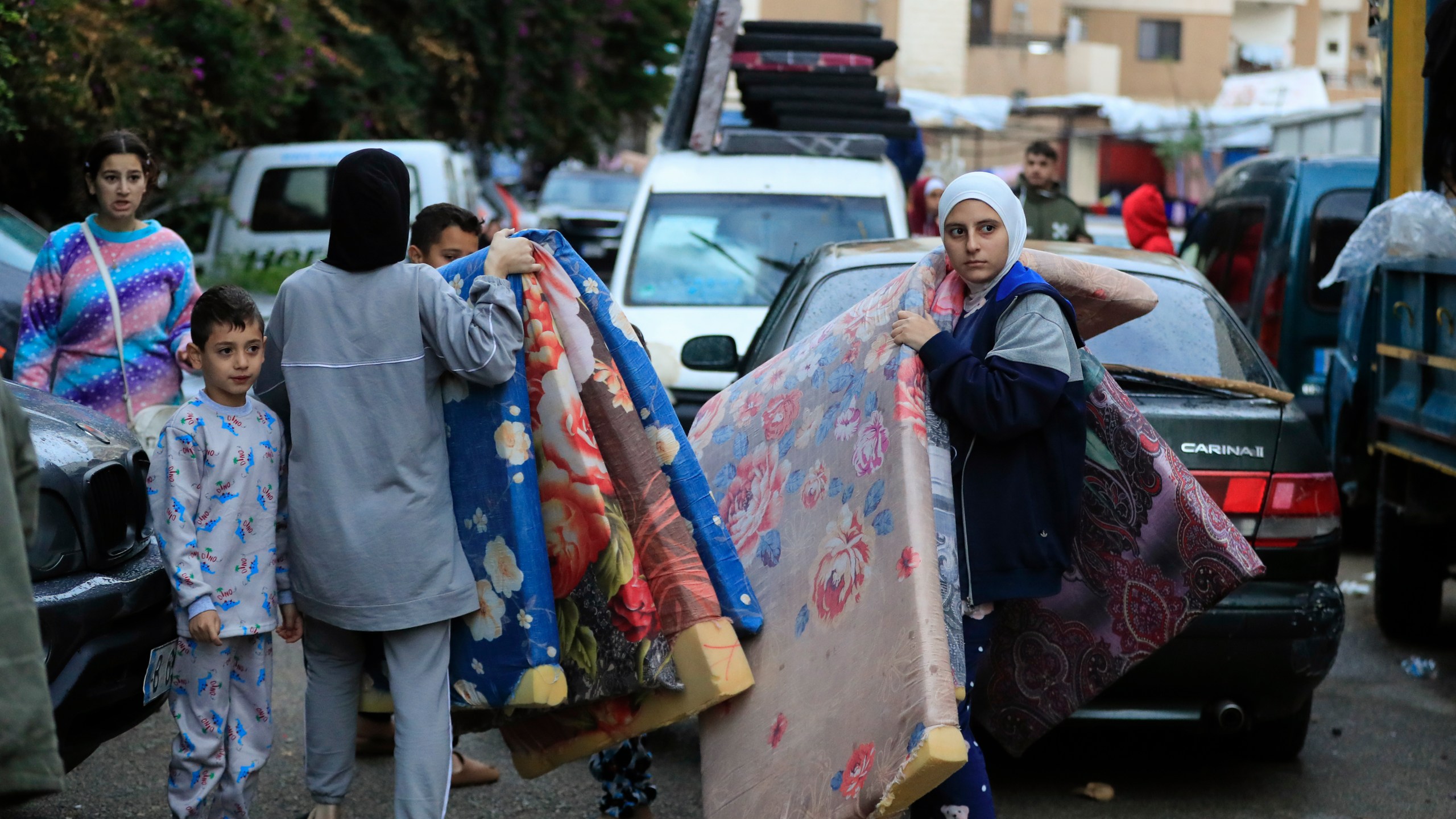 Displaced families carry mattresses as they prepare to return to their villages after a ceasefire between Israel and Hezbollah went into effect in Sidon, Lebanon, Wednesday, Nov. 27, 2024. (AP Photo/Mohammed Zaatari)