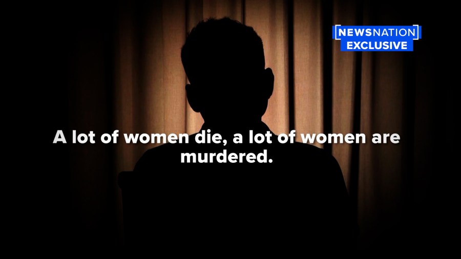 An unidentifiable man sits in a dark room during an interview.