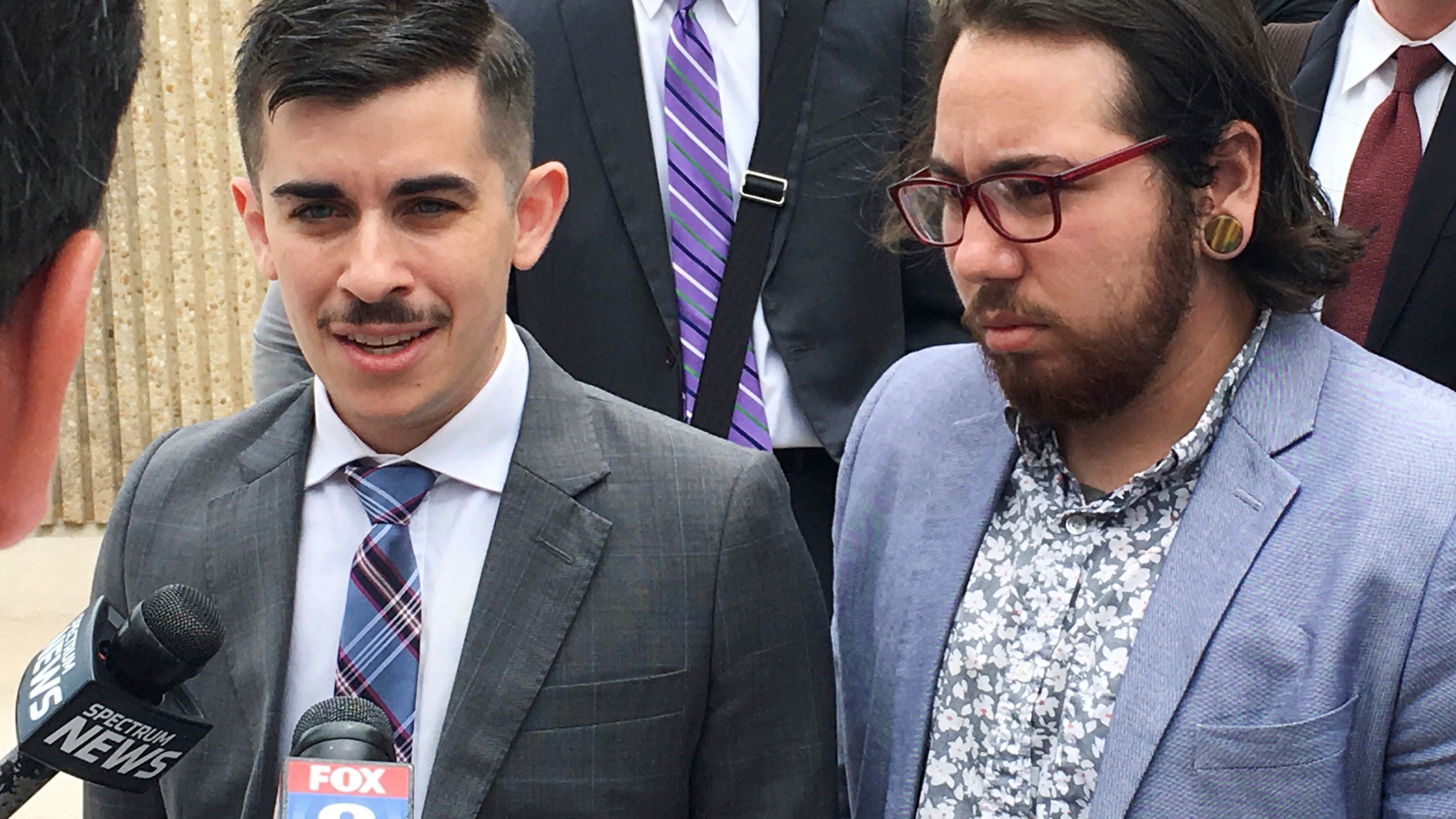 FILE - ACLU lawyer Chase Strangio, left, and plaintiff Joaquin Carcano address reporters after a hearing, June 25, 2018, in Winston-Salem, N.C., on their lawsuit challenging the law that replaced North Carolina's "bathroom bill." Carcano and other transgender plaintiffs argue the new law continues to discourage transgender people from using restrooms that match their gender identity. (AP Photo/Jonathan Drew, File)
