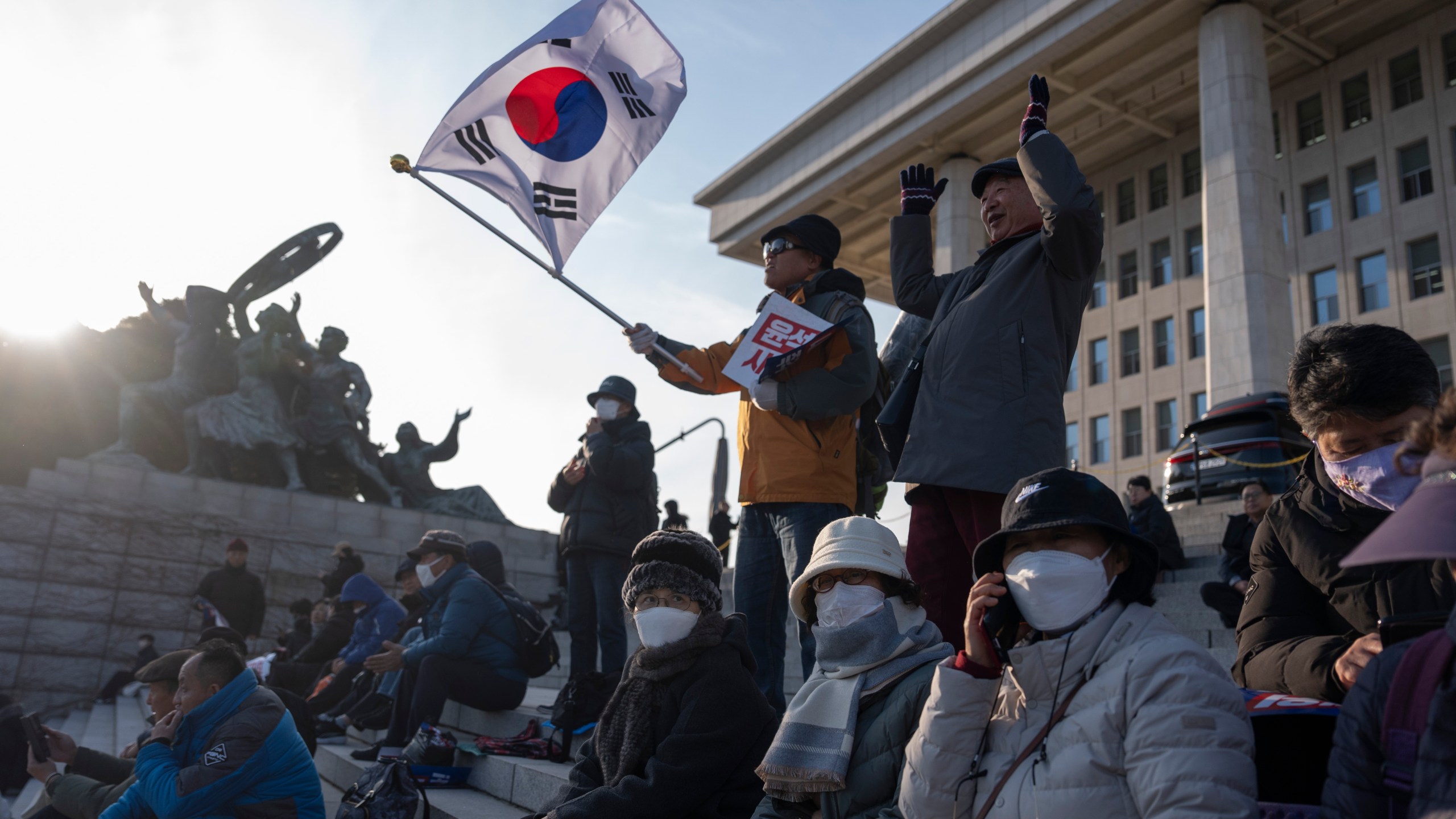 A protester waves a South Korean flag as he joins others gathering outside the National Assembly in Seoul, South Korea, Wednesday, Dec. 4, 2024. (AP Photo/Ng Han Guan)