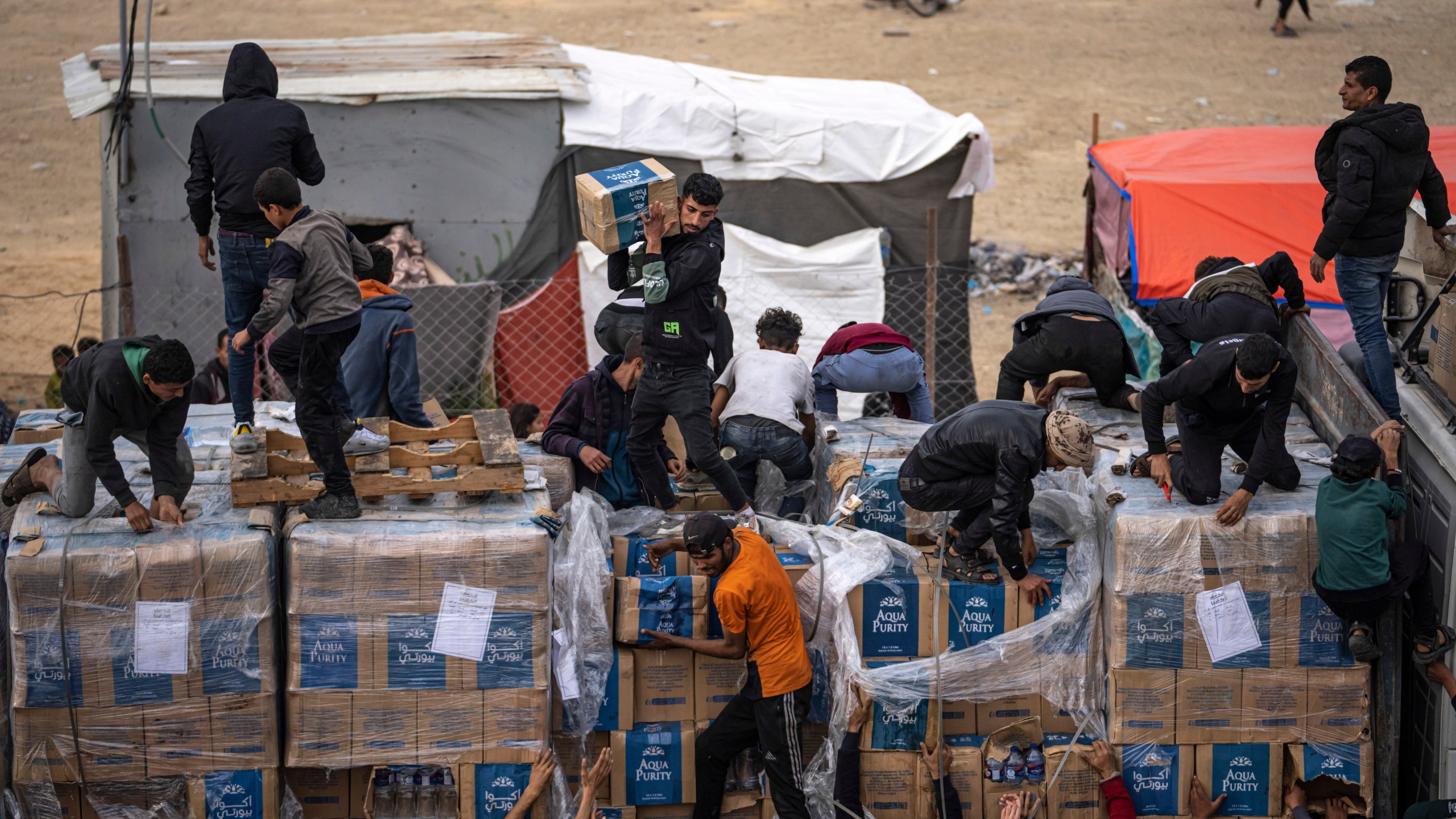 FILE - Palestinians grab humanitarian aid from a truck as it crossed into the Gaza Strip in Rafah, Dec. 17, 2023. (AP Photo/Fatima Shbair, File)