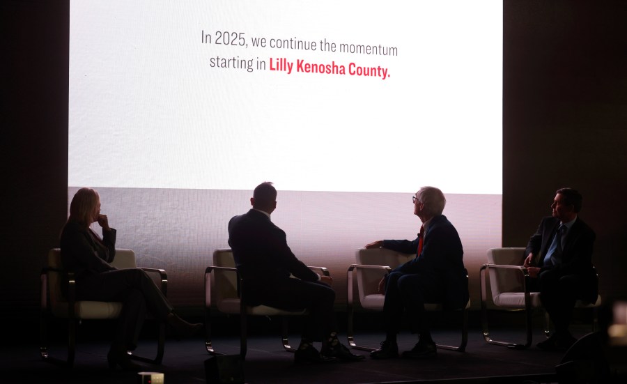 Kenosha County Executive Samantha Kerkman, from left, Edgardo Hernandez, executive vice president and president of Lilly manufacturing operations, Gov. Tony Evers, and David Ricks, chair and CEO of Eli Lilly, watch a video during the announcement that Eli Lilly is expanding in Wisconsin Thursday, Dec. 5, 2024, in Kenosha, Wis. (Sean Krajacic/The Kenosha News via AP)