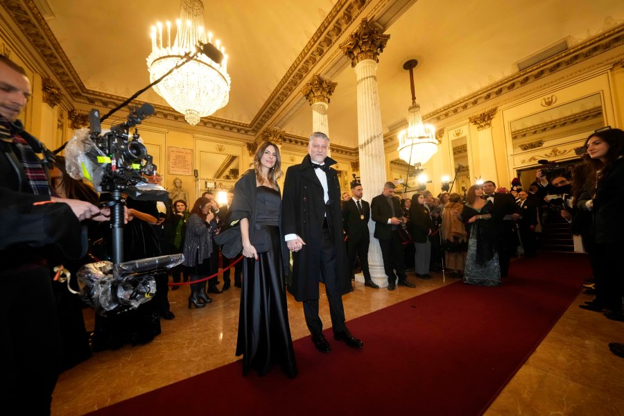 Italian Culture Minister Alessandro Giuli is flanked by his wife Valeria Falcioni as they arrive at Milan's Opera House La Scala, Italy, for the opening of the 2024-25 season featuring Giuseppe Verdi's 'La Forza del destino', Saturday, Dec. 7, 2024. (AP Photo/Luca Bruno)