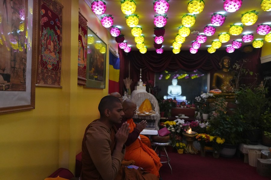 Monks chant sutras in Pāli language next to a flowered-decorated altar overlooking a giant Buddha statue in the yard of the New Jersey Buddhist Vihara and Meditation Center in Franklin Township, N.J. on Sunday Nov. 30, 2024. (AP photo/Luis Andres Henao)