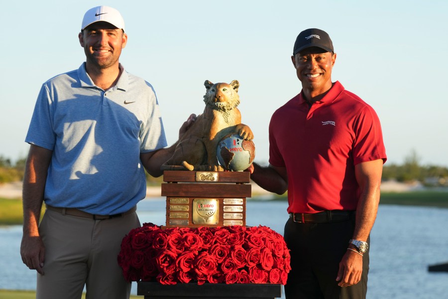 Scottie Scheffler, izquierda, de Estados Unidos, y Tiger Woods, posan con el trofeo del campeonato después de la ronda final del torneo Hero World Challenge del PGA Tour, en el Club de Golf Albany, en New Providence, Bahamas, el domingo 8 de diciembre de 2024. (AP Foto/Fernando Llano)