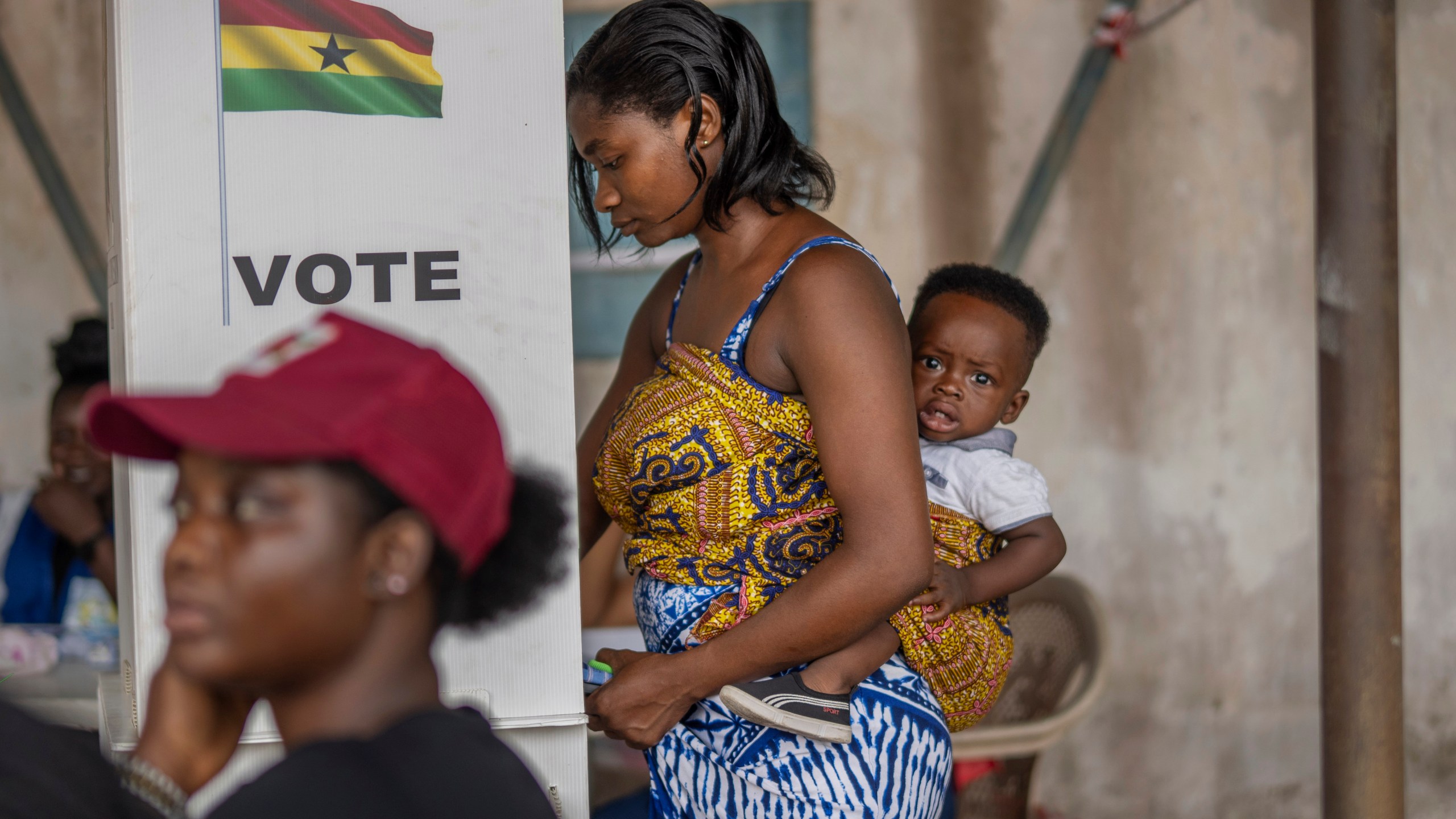 A woman with her child prepares her ballot in the general elections in Accra, Ghana, Saturday, Dec. 7, 2024 (AP Photo/Jerome Delay)