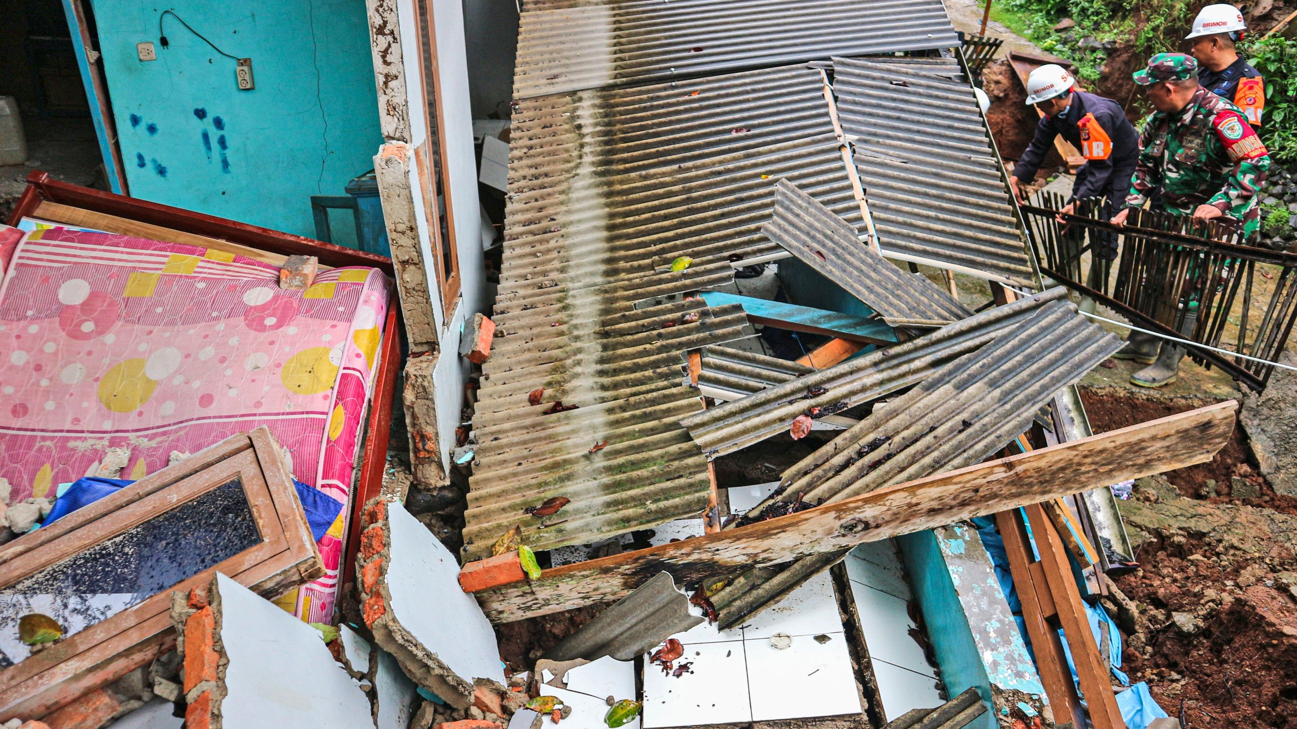 Rescuers clear up rubble from damaged houses at a neighborhood affected by a landslide in Sukabumi, West Java, Indonesia, Monday, Dec. 9, 2024. (AP Photo/Rangga Firmansyah)