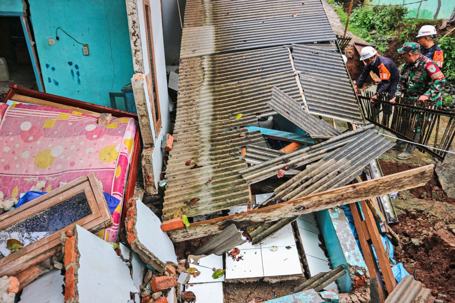 Rescuers clear up rubble from damaged houses at a neighborhood affected by a landslide in Sukabumi, West Java, Indonesia, Monday, Dec. 9, 2024. (AP Photo/Rangga Firmansyah)