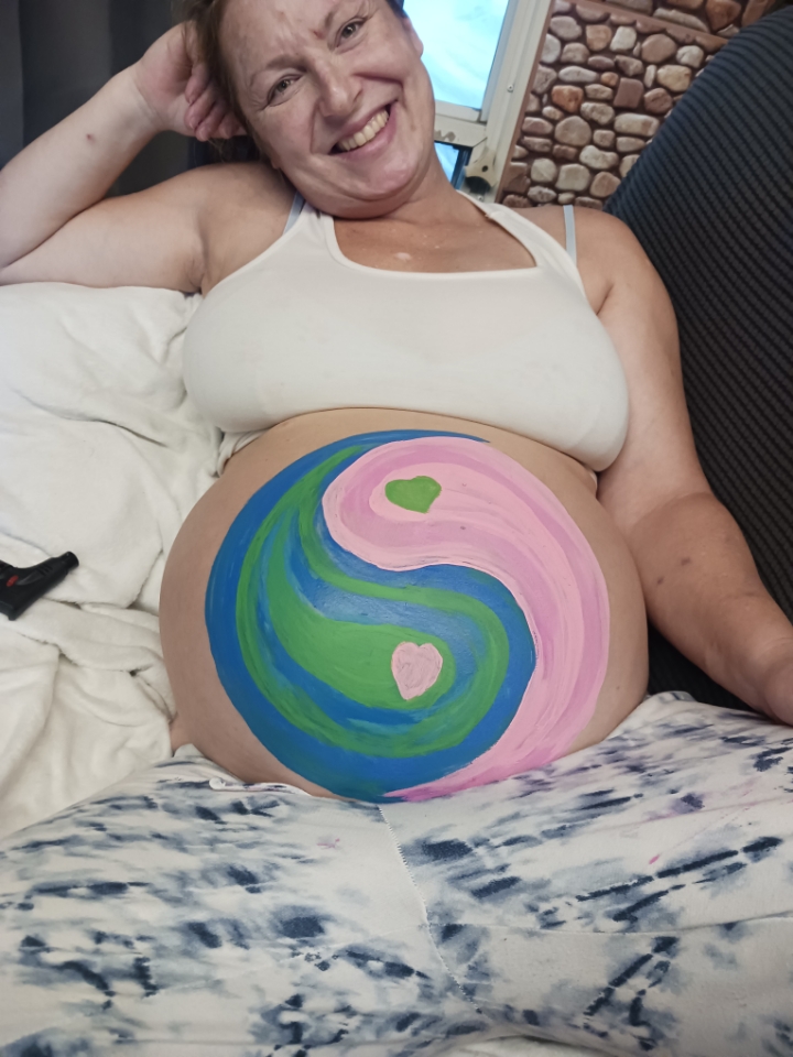 A pregnant woman with a yin-yang symbol painted on her stomach.