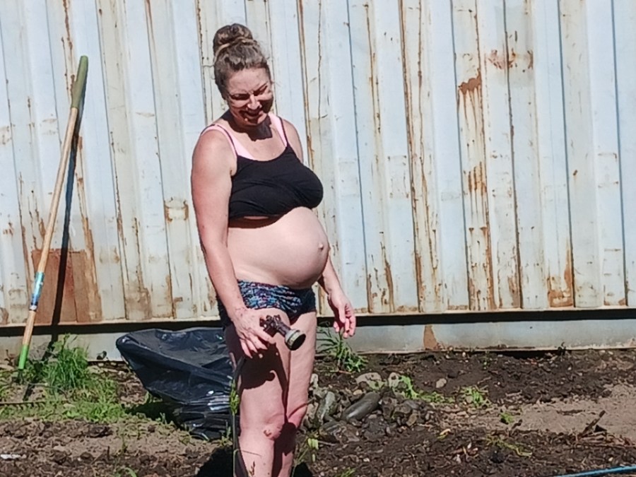 A pregnant woman in shorts and sports bra
